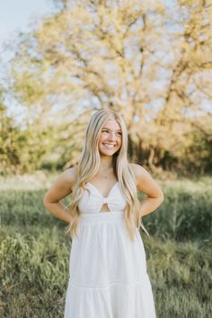 a woman in a white dress posing for the camera with her hands on her hips