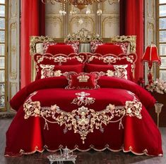 a red bed with gold trimmings in a room next to a chandelier