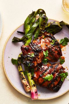 two grilled meats and asparagus on a purple plate next to a glass of wine