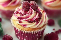 a cupcake with white frosting and raspberries on top, surrounded by berries