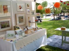 a table with pictures and decorations on it in front of a tent at an outdoor event