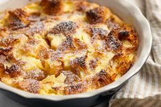 a casserole dish is covered with powdered sugar and sits on a striped cloth