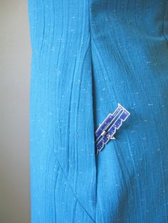 a close up of a person wearing a blue suit with a tie clip on it