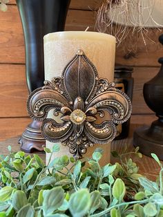 a candle is sitting on a table next to some plants and other decorating items