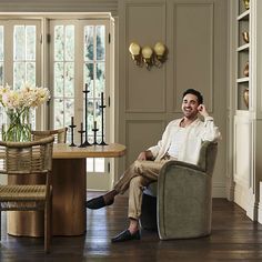 a man sitting in a chair talking on a cell phone next to a table and chairs