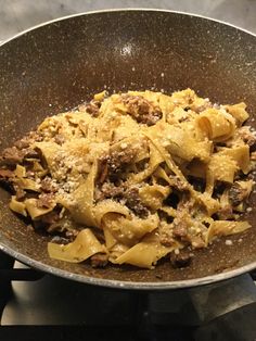 a pan filled with pasta and meat on top of a stove