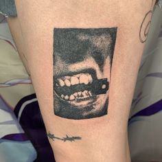 a black and white photo of a person's mouth with teeth on his leg