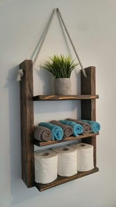 a wooden shelf holding several rolls of toilet paper and a potted plant on it