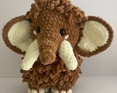 an elephant stuffed animal with white tusks and brown ears sitting on a table