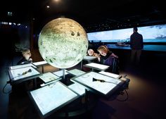 people looking at an illuminated globe in a museum