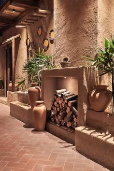 an outdoor fireplace with potted plants and firewood