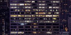 an aerial view of skyscrapers at night in new york city, with many windows lit up