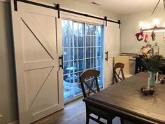 a dining room table with two chairs and sliding barn doors on the wall behind it