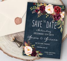 an elegant floral save the date card on top of a piece of wood with envelope and wax stamp