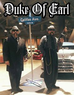 two men standing next to each other in front of a sign that says duke of car