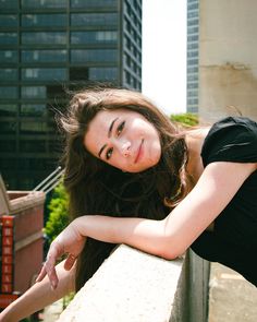 a beautiful young woman leaning on a ledge