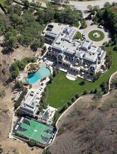 an aerial view of a large mansion with a swimming pool and tennis court in the foreground