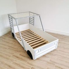 a white bed frame sitting on top of a hard wood floor next to a wall