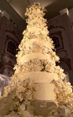 a large white wedding cake sitting on top of a table covered in lots of flowers