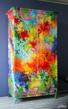 a colorful painted armoire sitting on top of a wooden floor