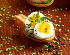 two small wooden spoons filled with food on top of a brown table covered in seeds