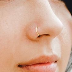 a woman's nose with a gold nose ring on her left side, and a small yellow nose pin in the middle