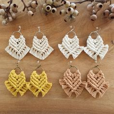 four pairs of woven earrings sitting on top of a wooden table