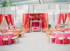 the tables are set up with pink and orange draping, gold chairs, and white linens