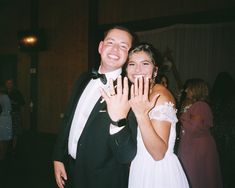 a man and woman standing next to each other holding their hands up in the air