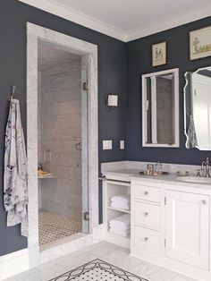 a bathroom with blue walls and white cabinets is pictured in this image, there are two mirrors on either side of the shower door