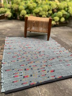 a wooden chair sitting on top of a rug next to a garden filled with green plants