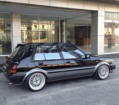 a black car is parked in front of a building with glass doors and windows on it