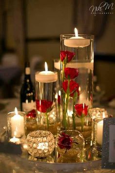 candles and roses are arranged in glass vases on a table with other items around it