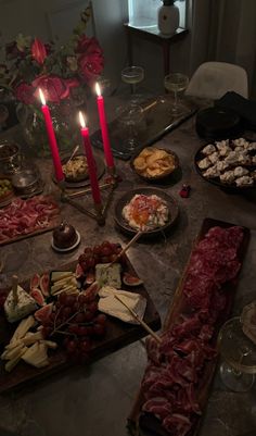 a table topped with lots of food next to two candles and plates filled with meat