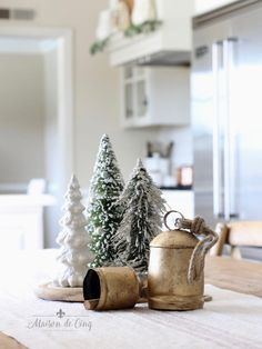 small christmas trees are sitting on a table in the kitchen, next to a coffee pot