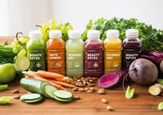 a variety of juices and vegetables on a table with fruits and vegetables around them