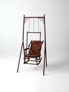 a brown leather chair sitting on top of a metal frame swing bed with chains hanging from it's sides