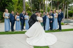 a bride and groom kissing in front of their wedding party