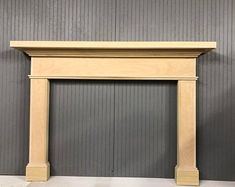 an unfinished fireplace mantel in front of a gray wall