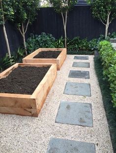 three wooden planters filled with dirt in a garden area next to trees and shrubbery