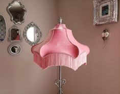 a lamp that is on top of a table next to a wall with pictures and mirrors