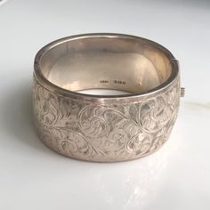 A vintage silver bangle with an ornate floral style. CONDITION: Wear consistent with age and use. Please see photos for more detail. HALLMARKED SILVER, ASSAYED IN BIRMINGHAM  APPROX. INTERNAL SIZE: BANGLE WIDTH: 31mm WEIGHT: 52.1g INTERNAL DIAMETER: 57mm x 52mm (CZ)