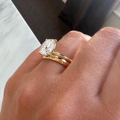 a person's hand with a gold ring and a white diamond on the finger