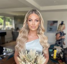 a woman with long blonde hair holding flowers