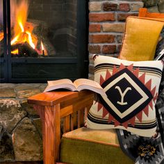 an open book sitting on top of a chair next to a fire in a fireplace