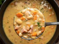 a spoon full of soup with ham and carrots