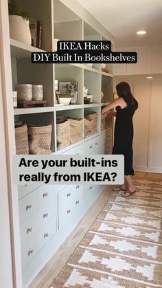 a woman standing in front of a white book shelf filled with books and baskets on top of it