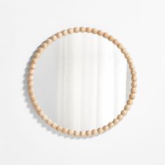 a round wooden beaded mirror on a white wall