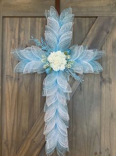 a blue cross decorated with white flowers and feathers