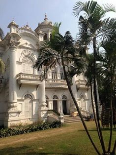 a large white building with palm trees in front